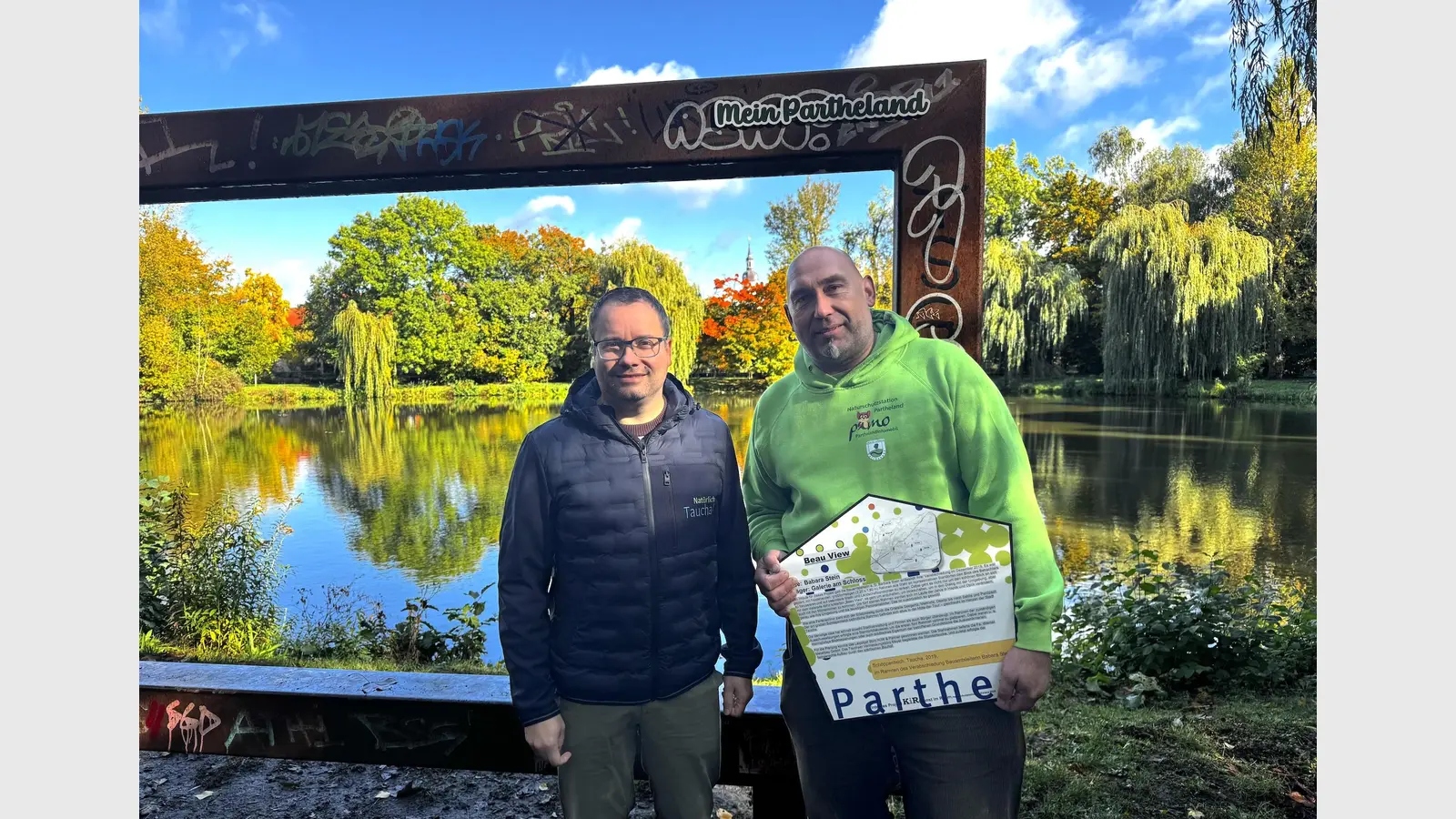 Bürgermeister Tobias Meier und Axel Weinert von der Naturschutzstation (v.l.) am BeauView-Rahmen am Schöppenteich, der seit heute den Zusatz „Mein Partheland” trägt. (Foto: Daniel Große [danielgrosse] (info@taucha-kompakt.de, dg24))