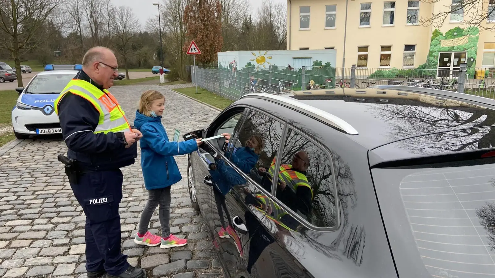Polizeihauptmeister Andree Weidner und eine Viertklässlerin bedanken sich bei einem rücksichtsvollen Autofahrer. (Foto: taucha-kompakt.de)