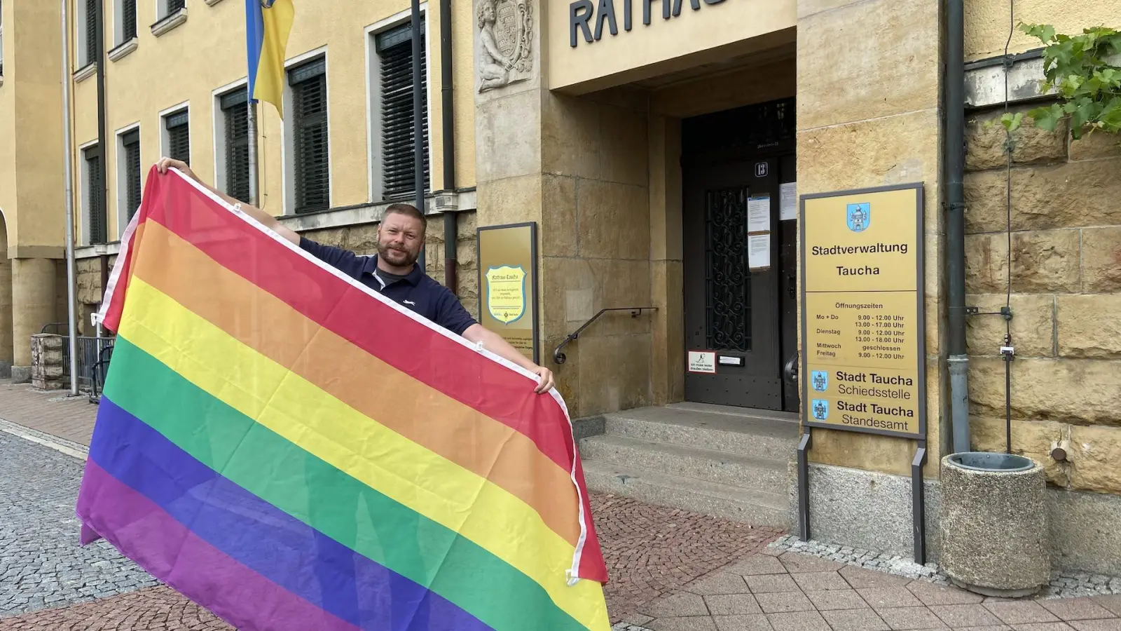 Nico Graumann, Verantwortlicher für Öffentlichkeitsarbeit der Stadt Taucha, präsentiert die Regenbogenflagge, die ab Montag am Rathaus wehen wird. (Foto: taucha-kompakt.de)