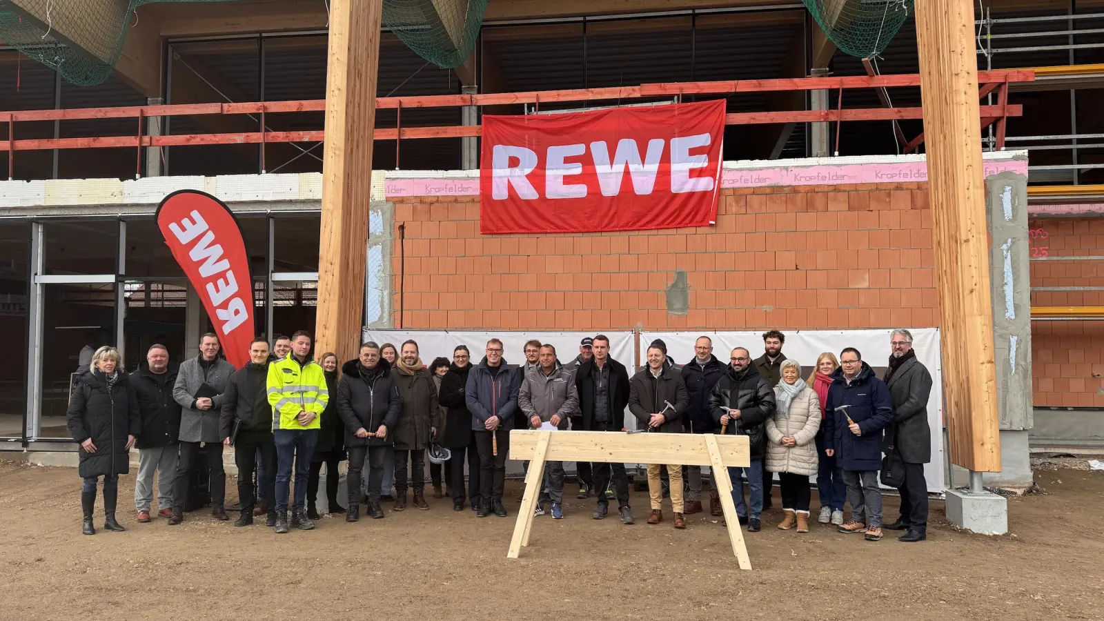 Gruppenfoto hinter Richtbock: Unter anderem mit Vertretern der Baufirmen, Projektverantwortlichen von REWE und Netto sowie Tauchas Bürgermeister Tobias Meier. (Foto: Daniel Große)