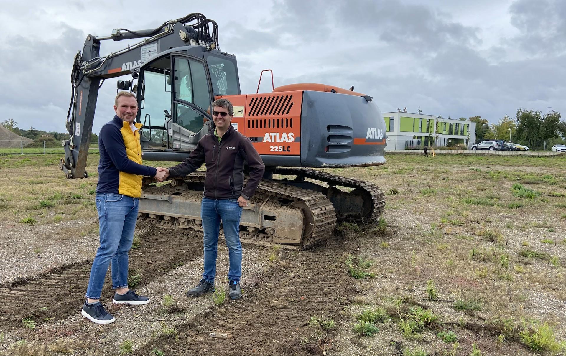 Handschlag vor dem soeben abgeladenen Bagger (noch ohne Schaufel): Hermann Schröder von der Schröder Holding GmbH (l.) und Christoph Schmidt von der Straßen- und Tiebau GmbH Osterfeld freuen sich über den Baubeginn. (Foto: taucha-kompakt.de)
