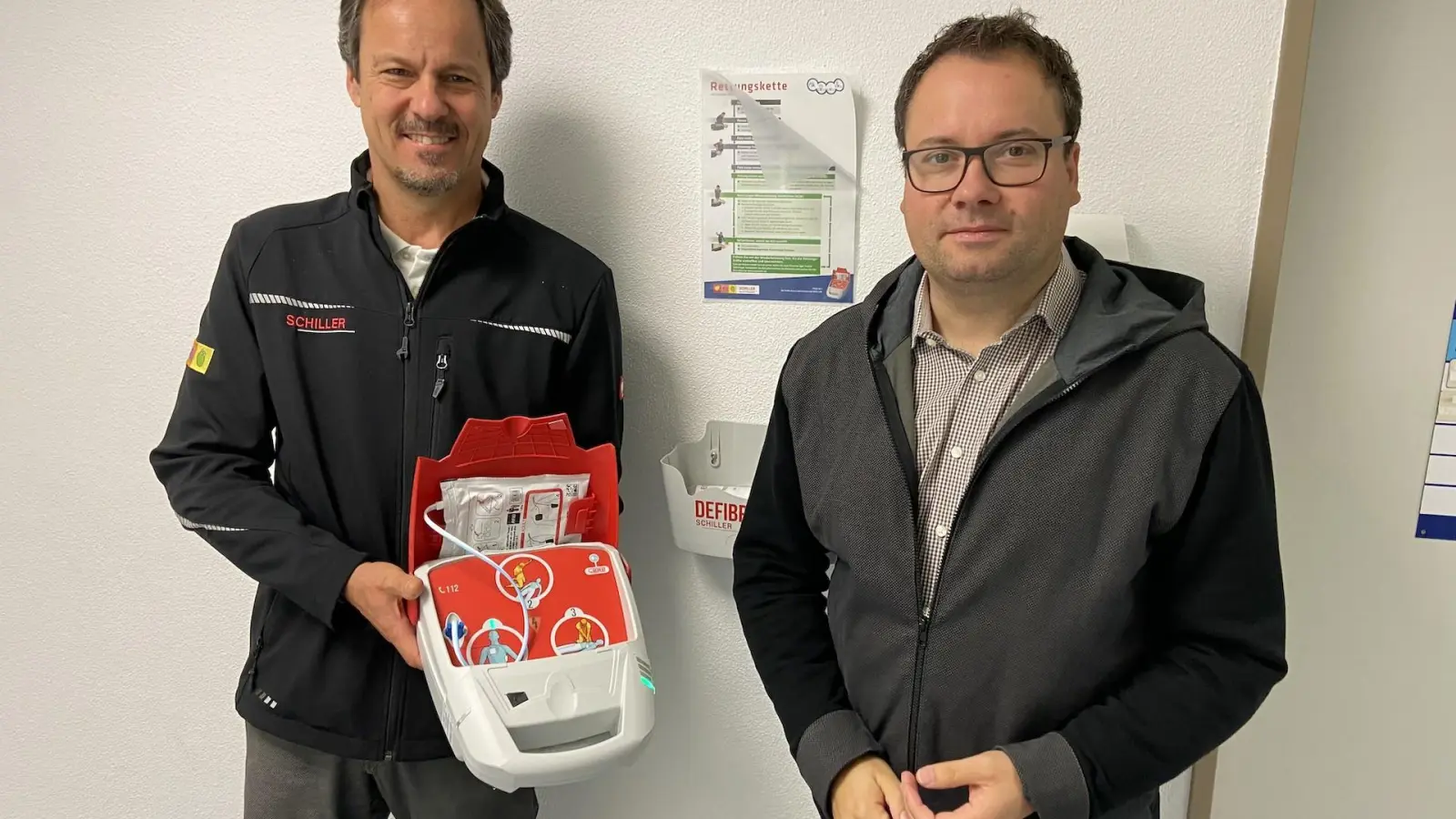 Christian Köhler mit dem Defibrillator “Fred” und Bürgermeister Tobias Meier in der Mehrzweckhalle Taucha. (Foto: taucha-kompakt.de)
